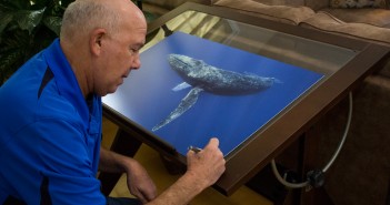 Marty Snyderman signing a print of his photo "Humpback Whales" which will be one of the prizes in the photo contest. Photo courtesy Marty Snyderman and Vivid-Pix