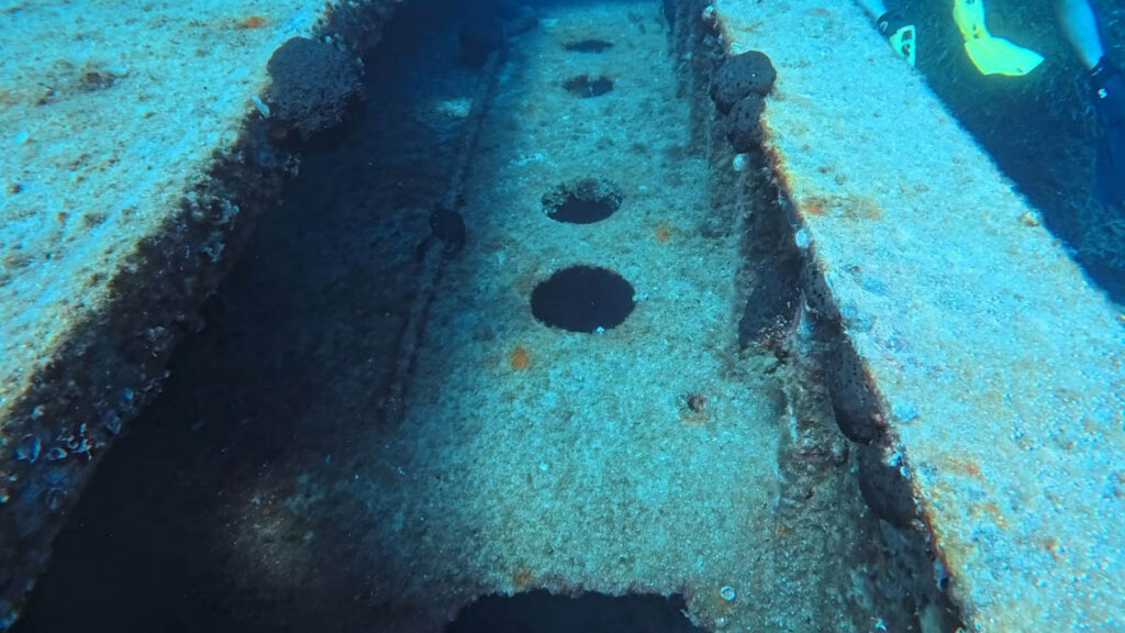 Close-up of a corroded metal section with circular openings inside the MV Città di Alessandria wreckage