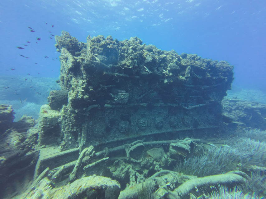 Large encrusted machinery remains lying on the seabed among scattered shipwreck components
